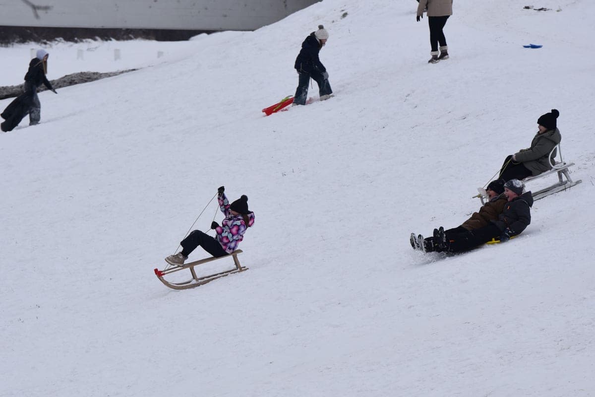 People sledding on a snowy hill in winter