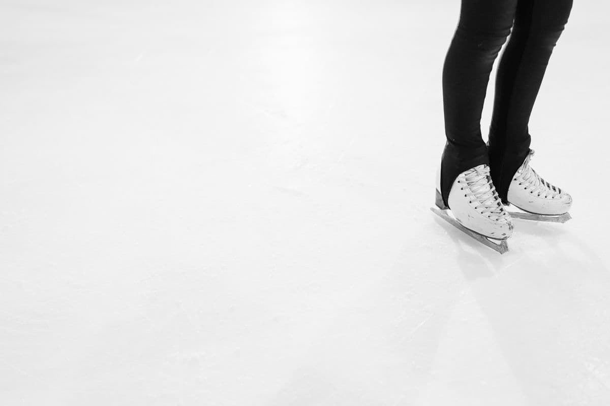 A pair of white ice skates standing on a clean indoor ice rink