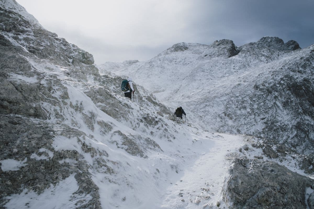 Hikers making their way along a snowy mountain trail in Italy