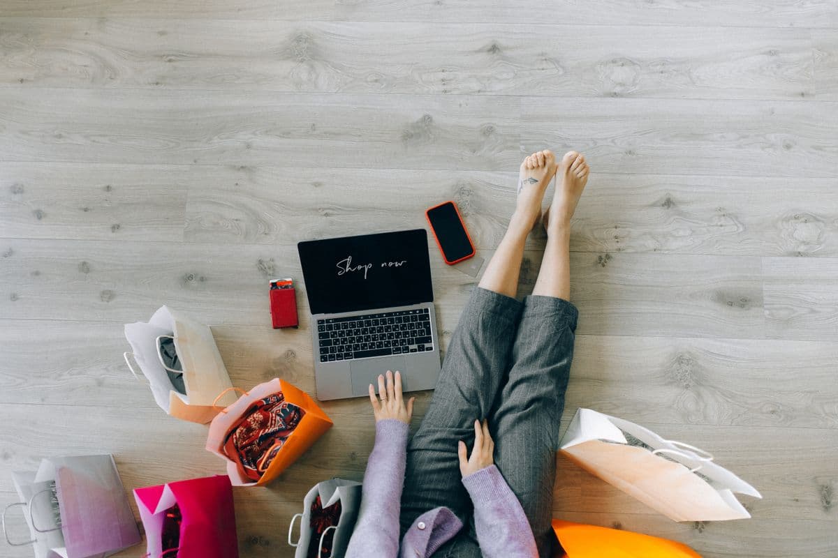 A person shopping online with a laptop and paper shopping bags