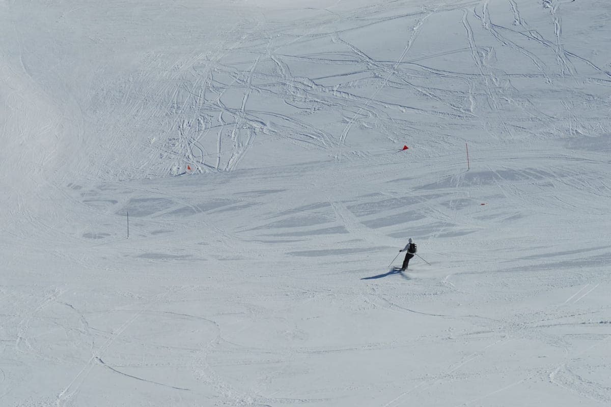 A lone skier crossing a wide snowy landscape leaving tracks behind