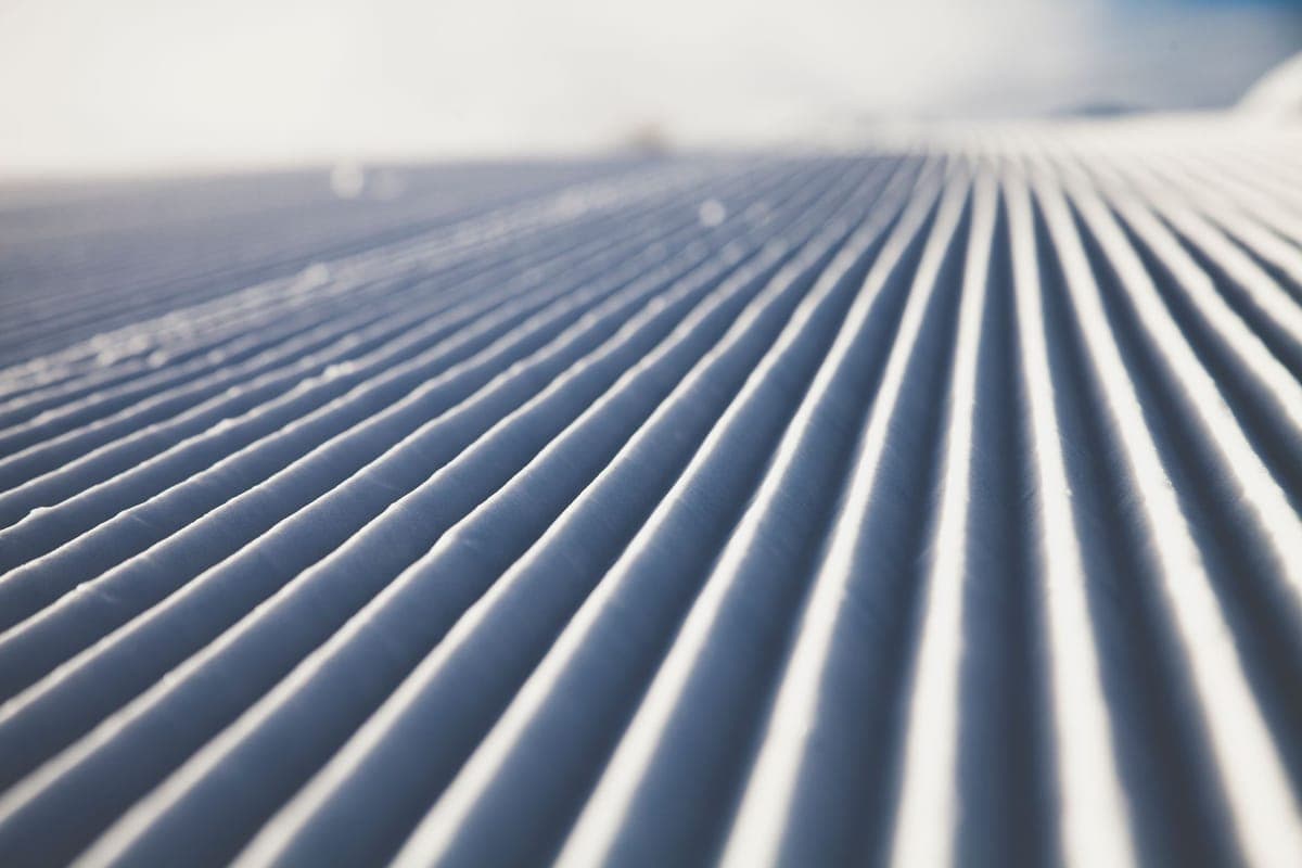 Close-up of groomed snow ridges forming a symmetrical winter pattern