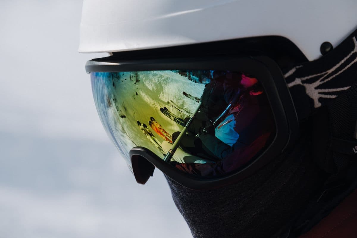Ski goggles reflecting skiers on a snowy slope