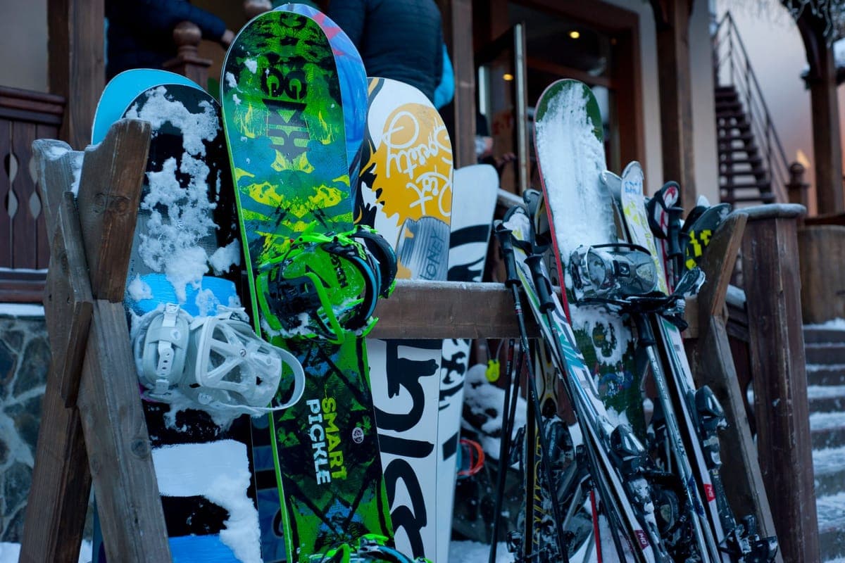 Skis and snowboards lined up outdoors at a winter ski lodge