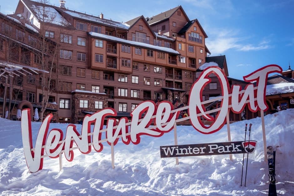 A ski resort with a signpost and skiers enjoying a sunny winter day