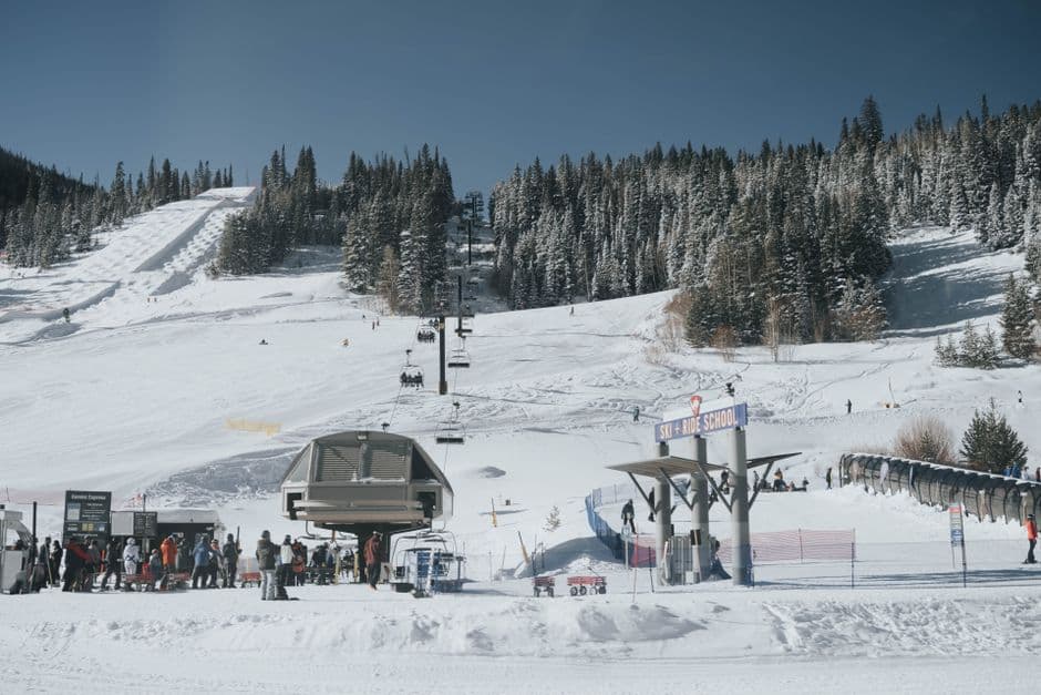 A busy ski resort with snow-covered slopes and people enjoying winter sports