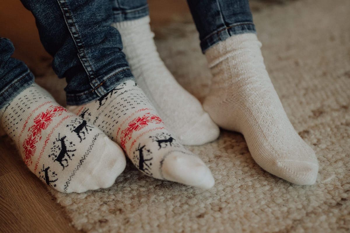 Two people in warm winter socks resting indoors on a carpet