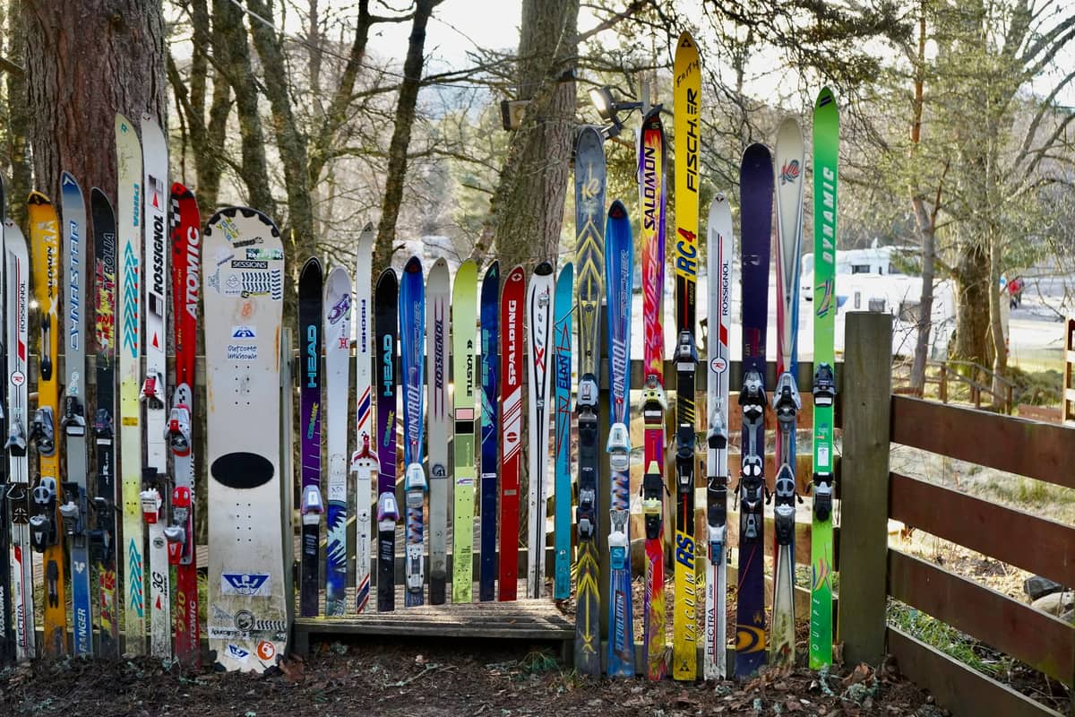 A display of skis and snowboards standing outdoors at a winter resort