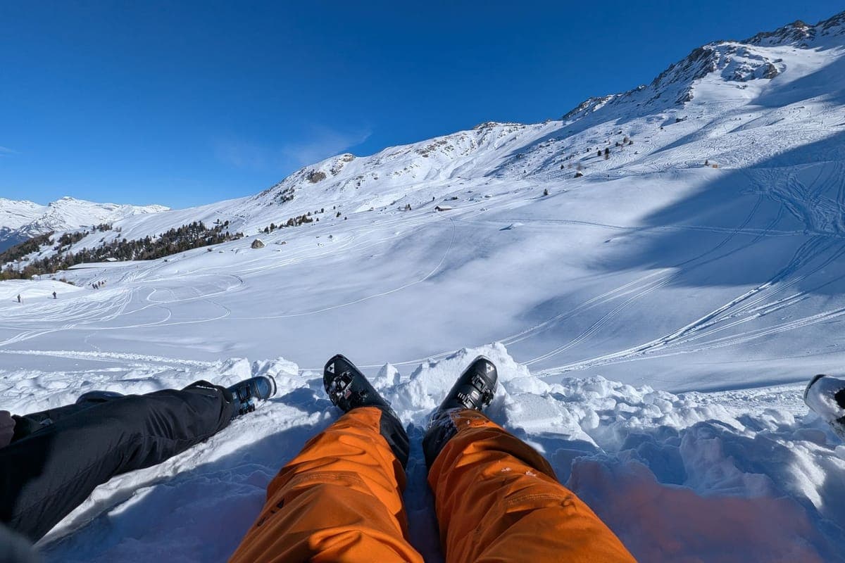 A skier descending an alpine slope with mountain views behind