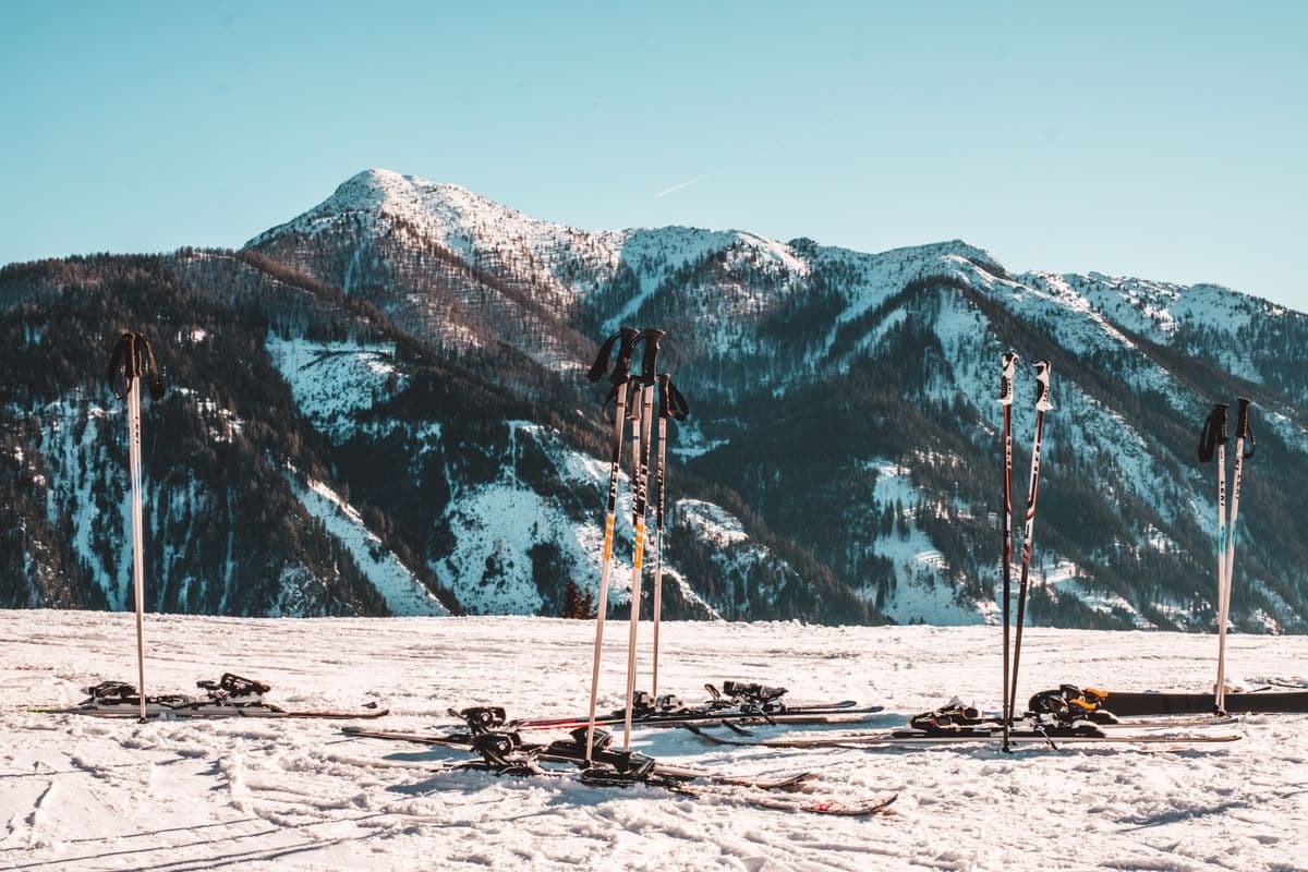 Ski equipment resting on a snowy slope with alpine peaks behind