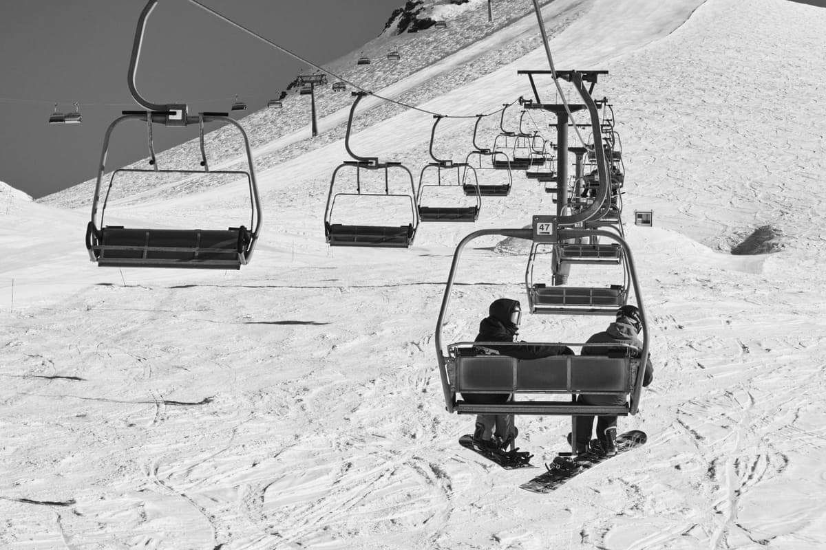 Skiers riding a chairlift above a snow-covered slope in winter
