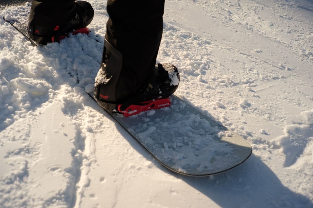 Close-up of a snowboarder's boots strapped into bindings on snow