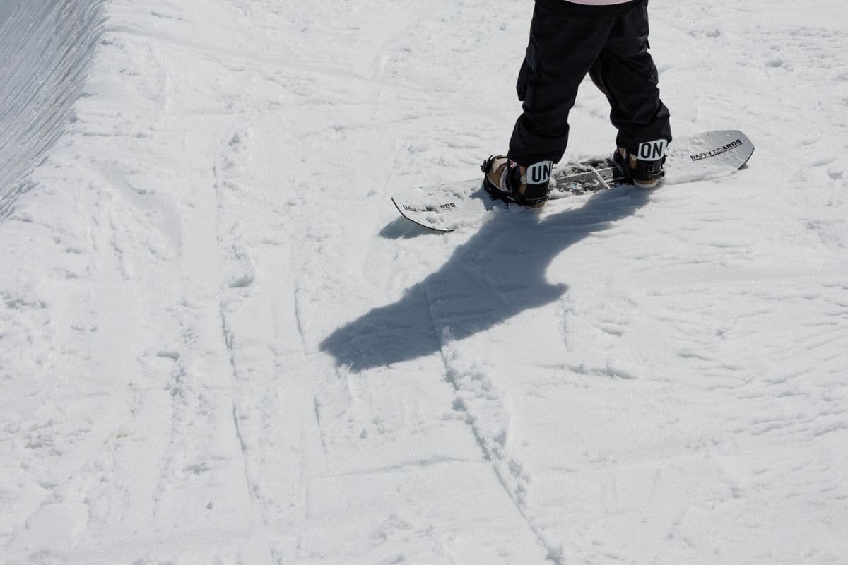 Close-up of a snowboarder on a snowy slope casting a long shadow