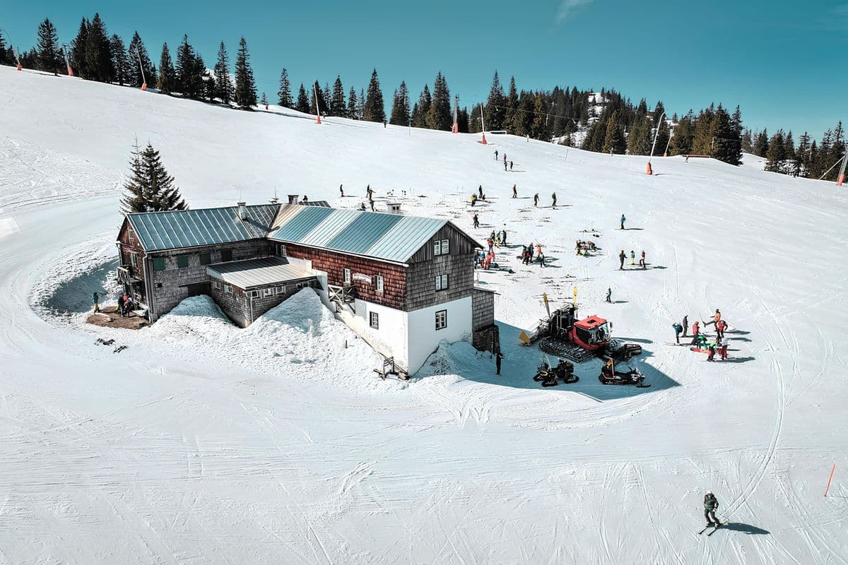 A winter scene at a ski resort with skiers and a snow-covered lodge