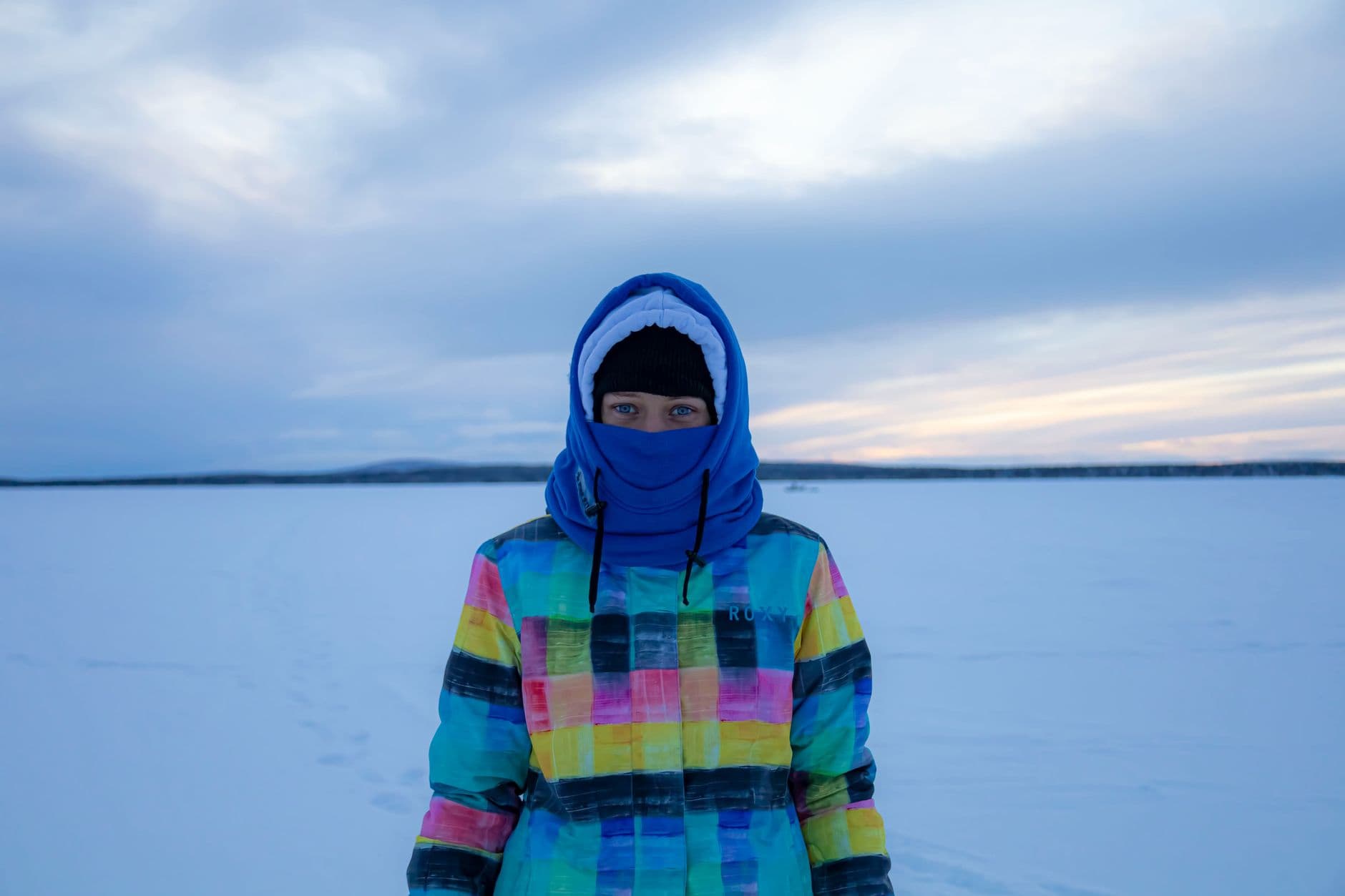 A person bundled in a bright winter jacket standing in a snow-covered landscape