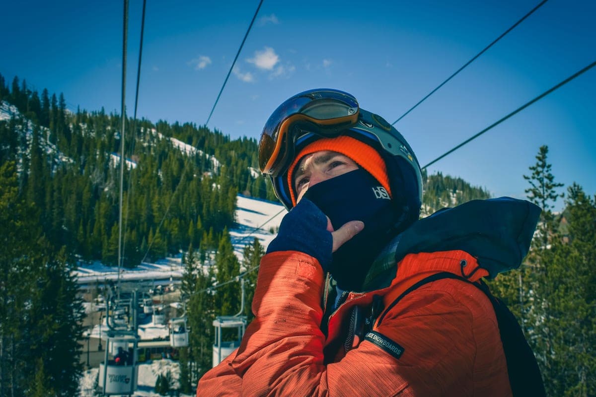 A skier in orange gear surrounded by snowy mountain scenery