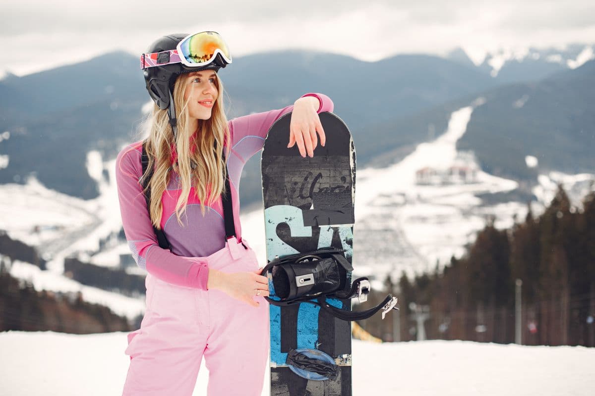 A snowboarder posing with a board at a snowy mountain resort