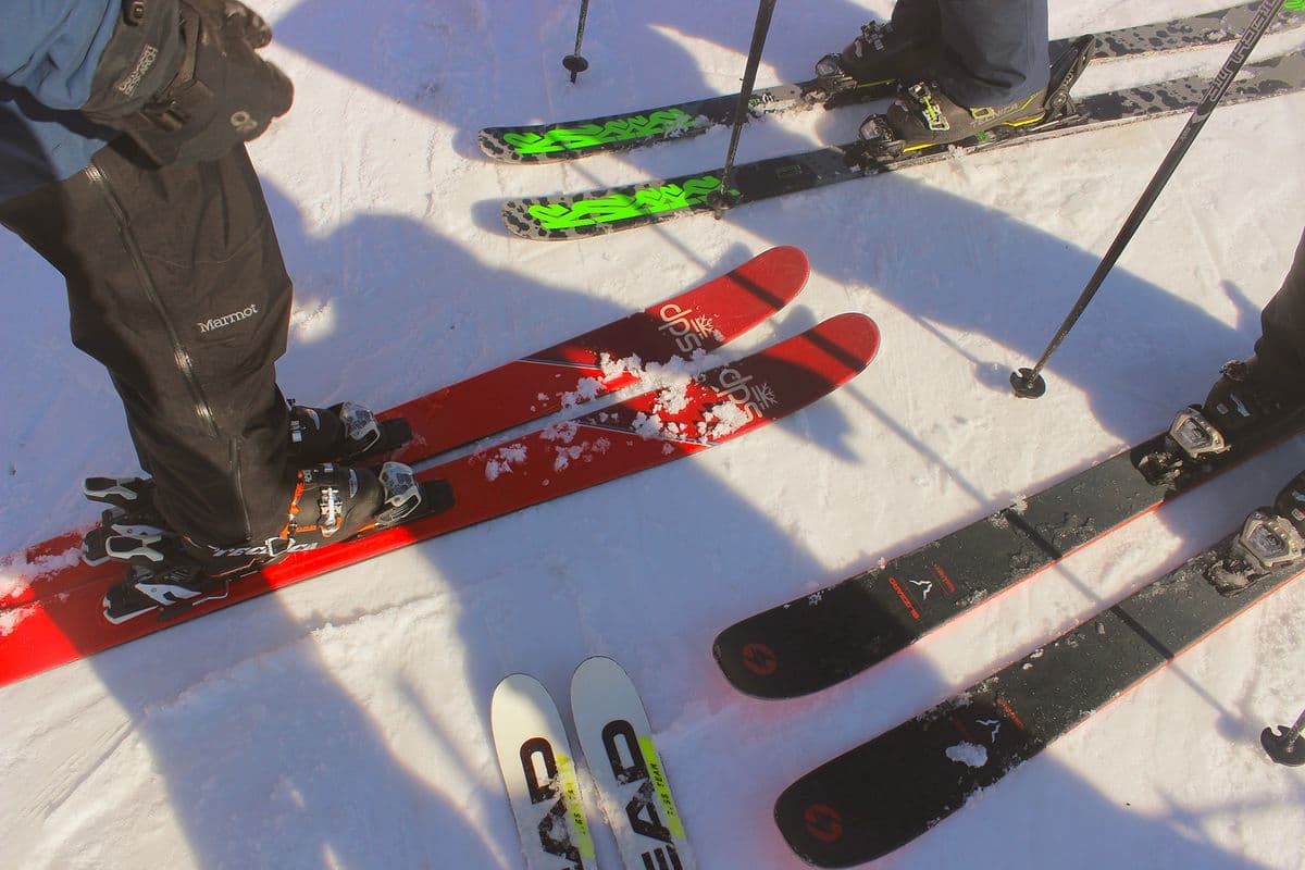 Skiers standing on a snowy slope with poles and equipment ready