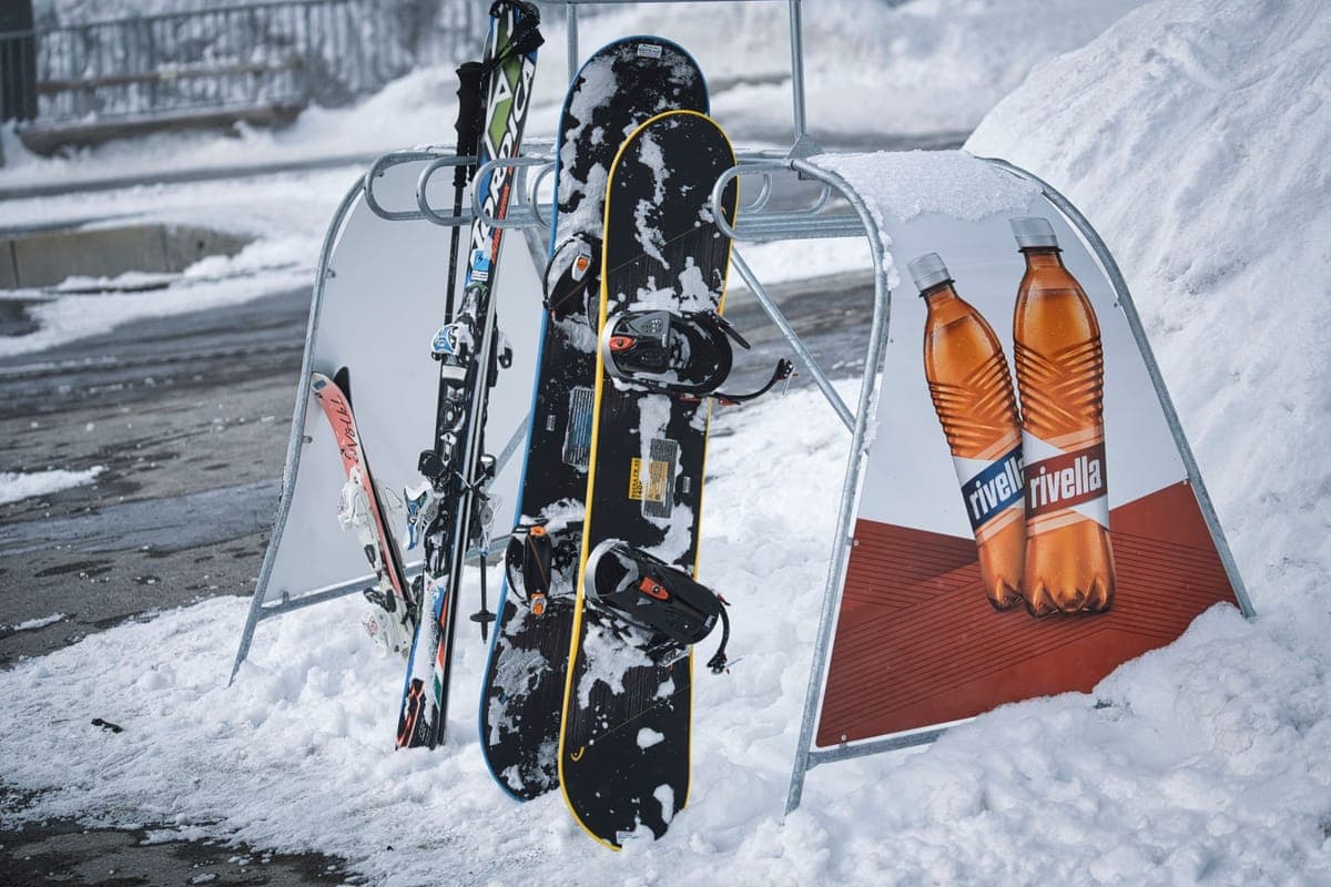 Skis and snowboards standing in the snow outside on a winter day