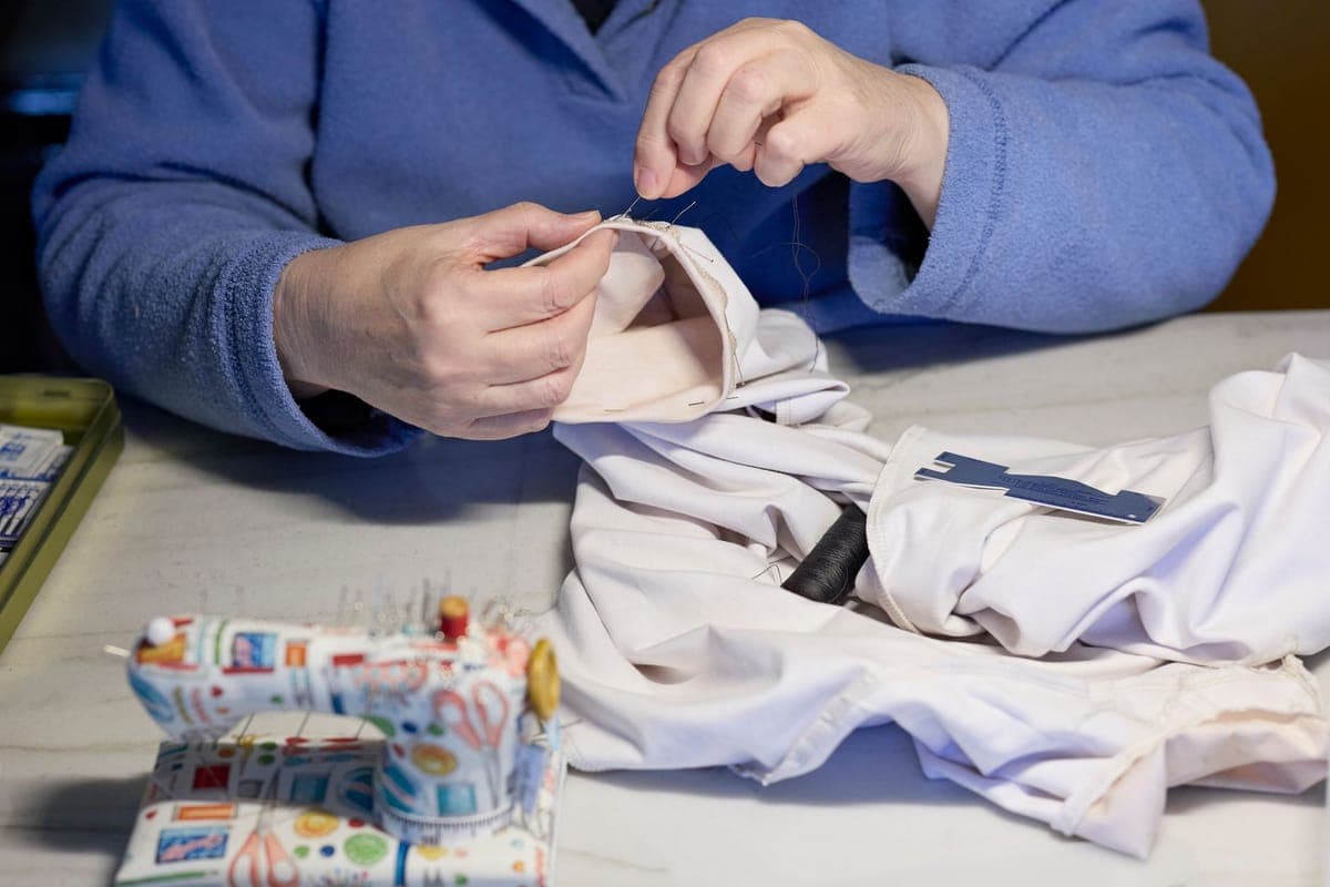 A person repairing a garment by hand with needle and thread
