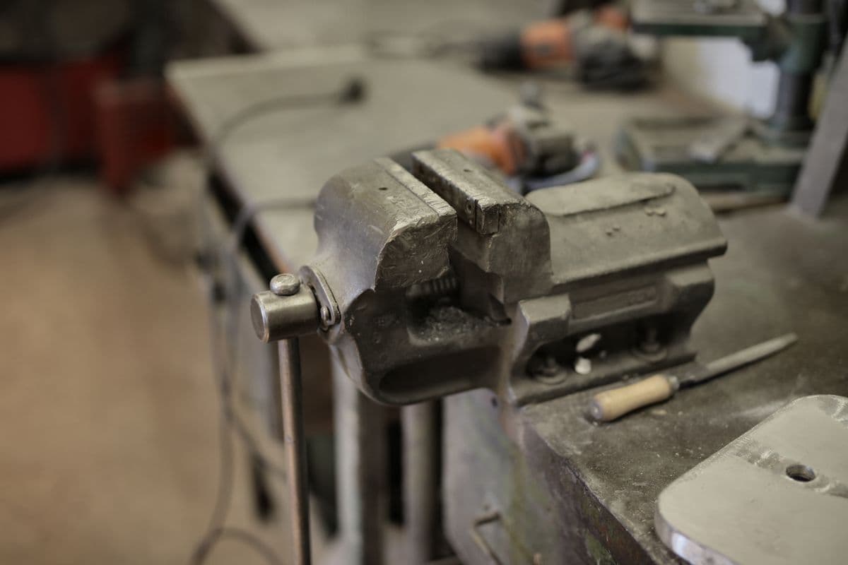 A vise fixed to a workbench surrounded by hand tools seen from above
