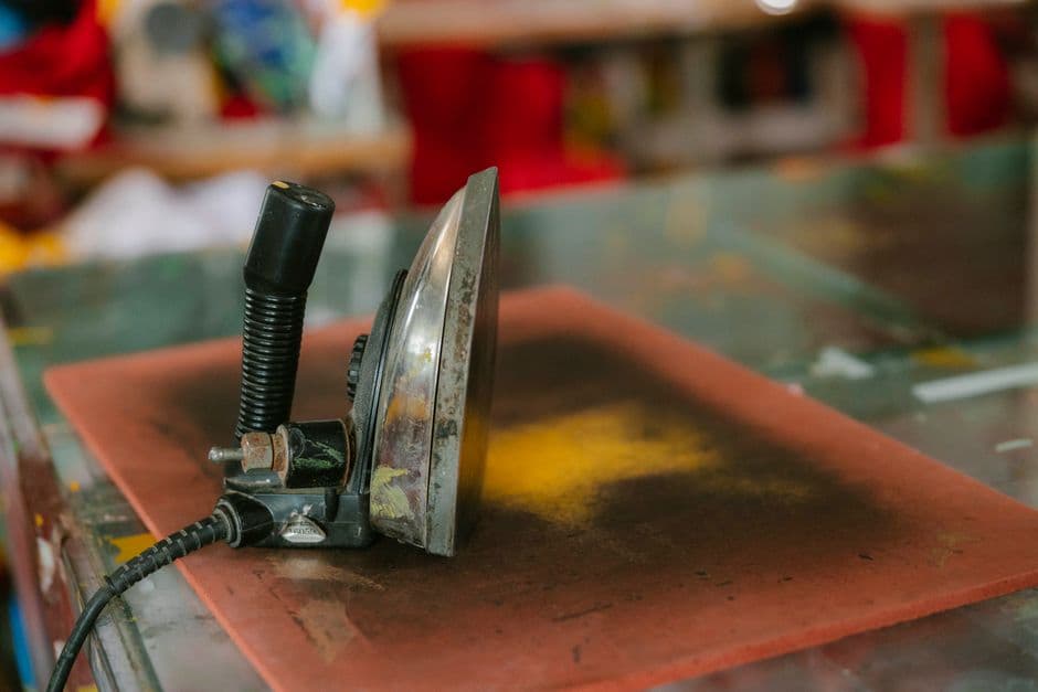 A clothes iron on a workshop table, the tool used for hot-waxing ski bases