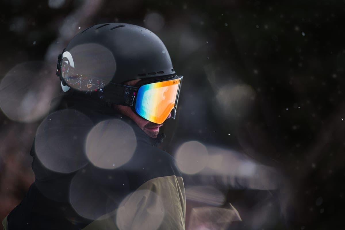 Close-up of a snowboarder wearing a helmet and reflective goggles