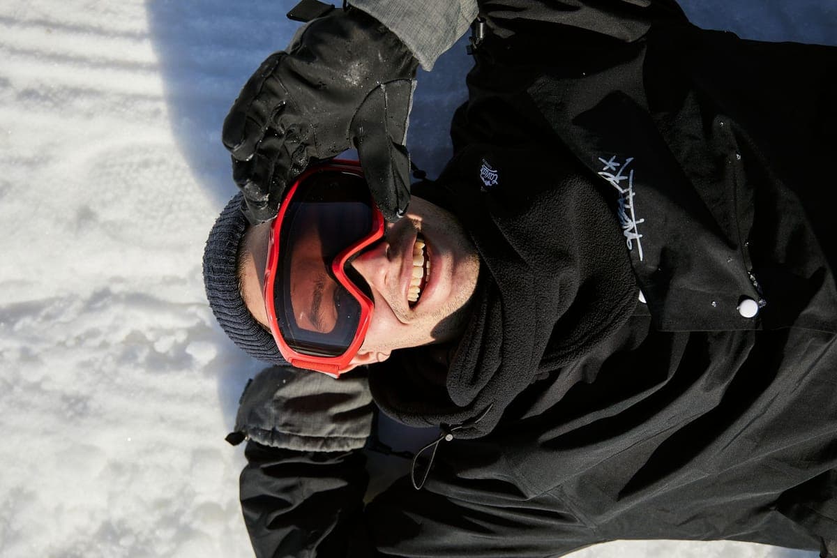 A person wearing protective goggles lying on snow in winter clothing