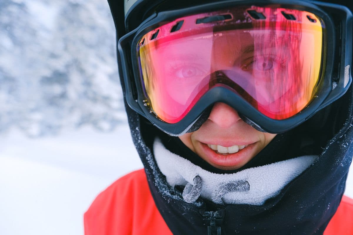Close-up of a snowboarder wearing goggles on a bright winter day