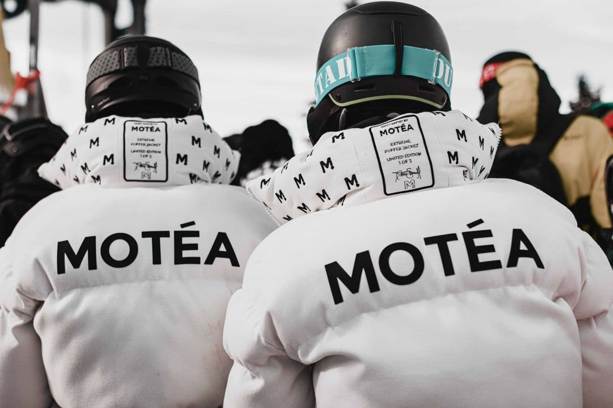 Skiers in white jackets seen from behind at a ski resort