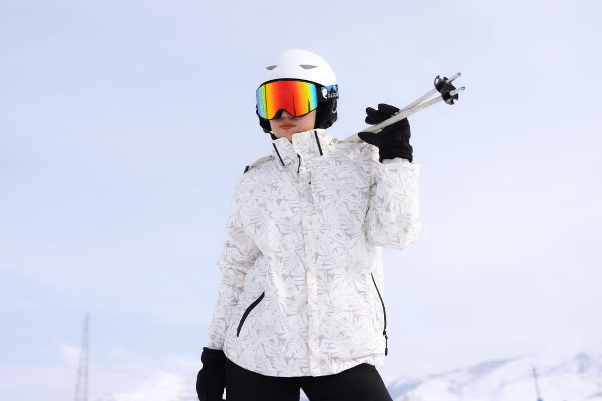 An adult skier in white gear on a bright snow-covered mountain