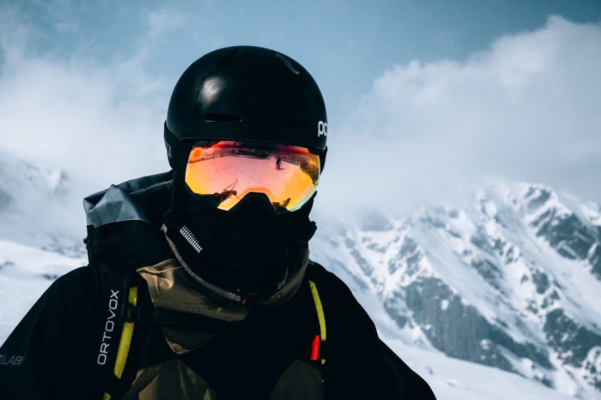 A skier in a helmet and goggles in a snowy mountain landscape