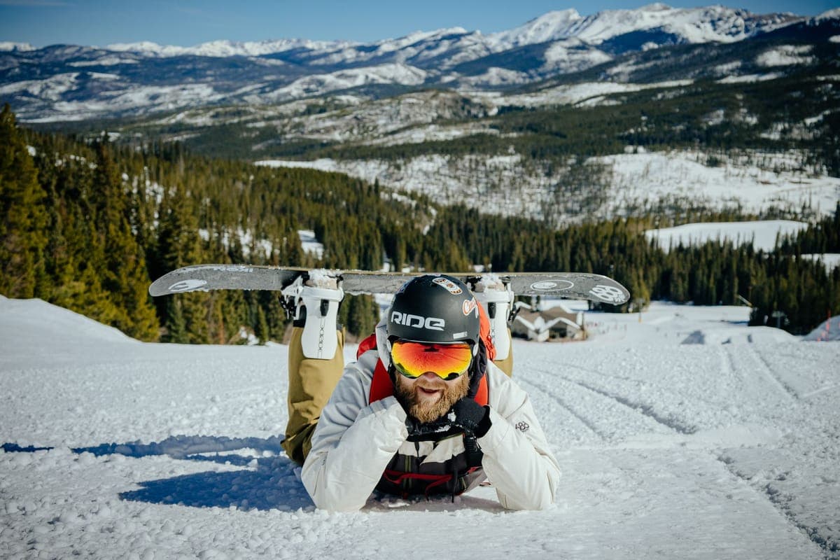 A snowboarder resting on a snowy mountain enjoying the winter view