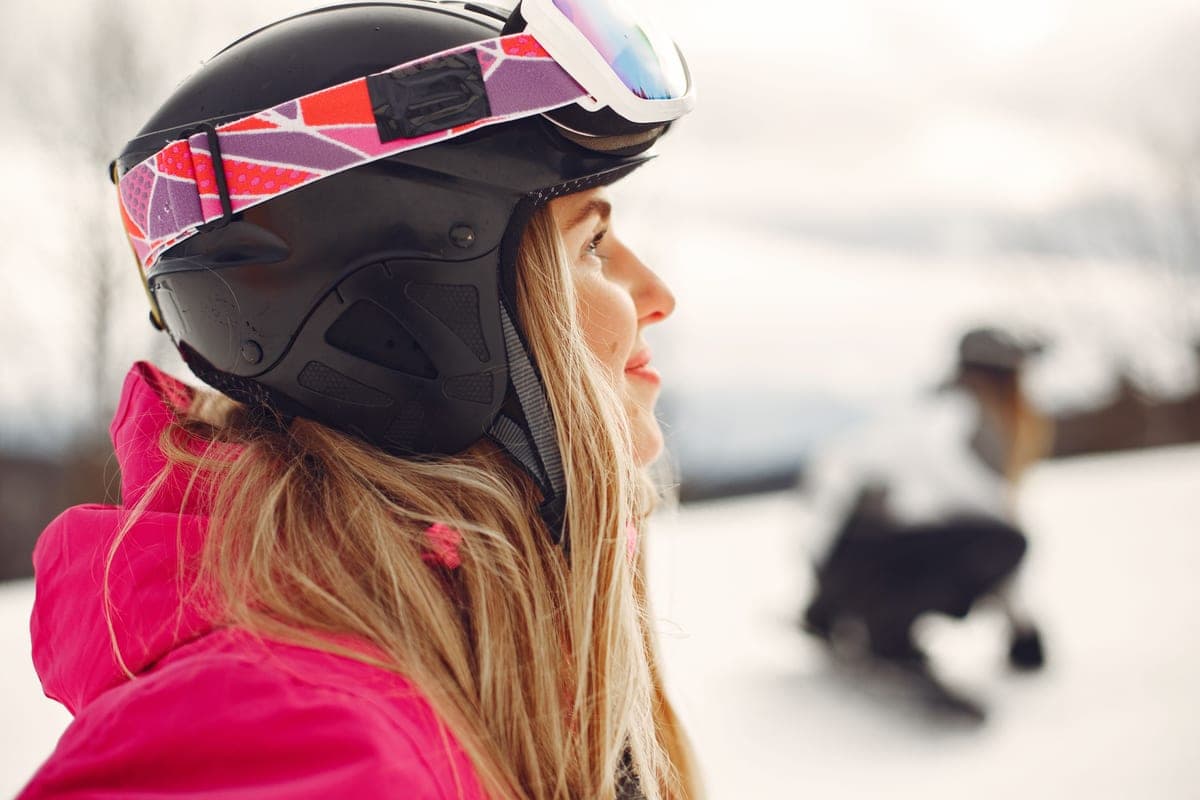 A skier in bright pink outerwear and a protective helmet