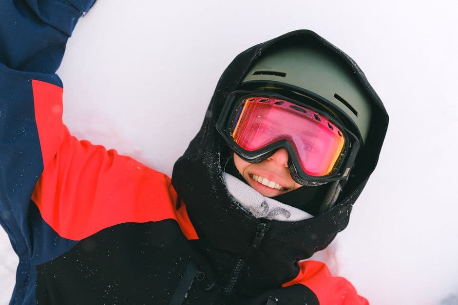 A snowboarder in a helmet and goggles resting on a snowy slope