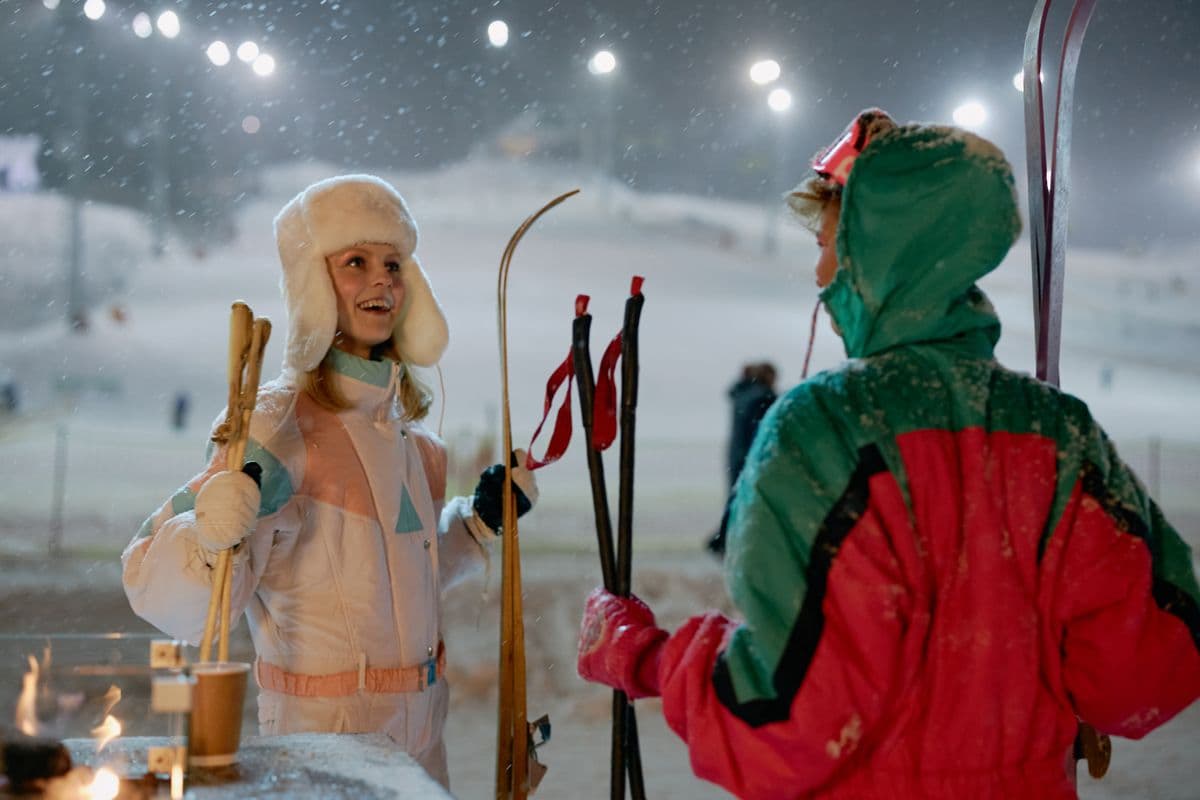 Smiling skiers in colorful winter gear on a snowy evening slope