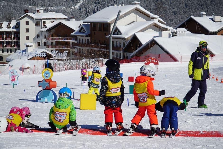 Children in bright ski outfits taking a lesson together on a snowy slope