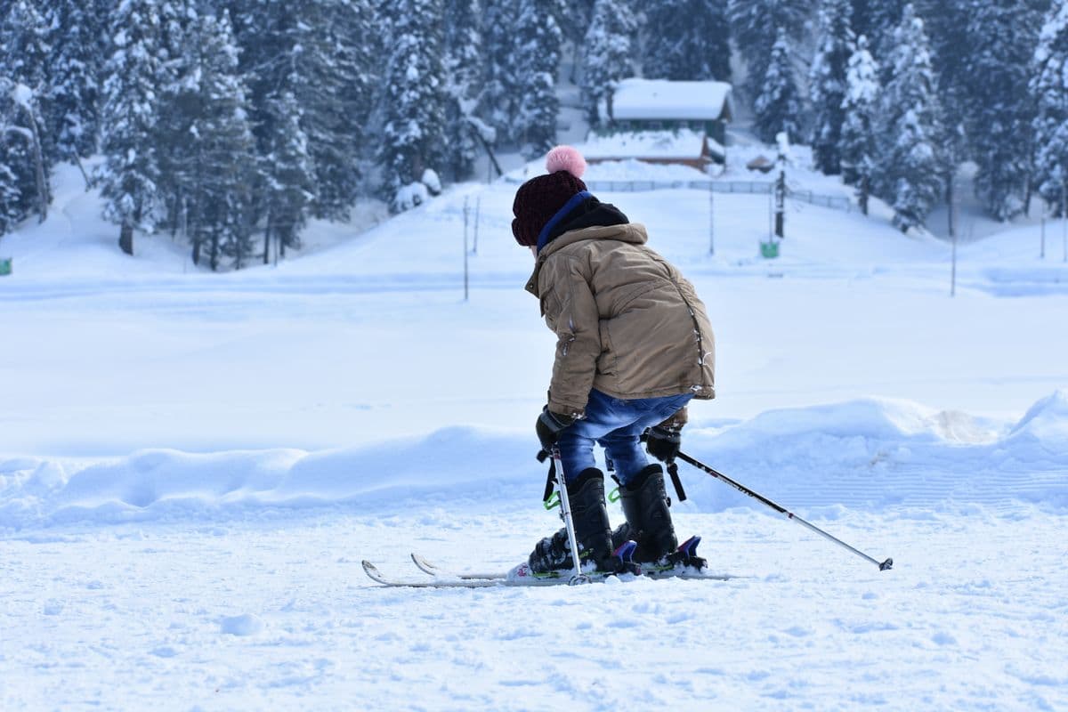 A child in a brown jacket skiing across a snowy landscape