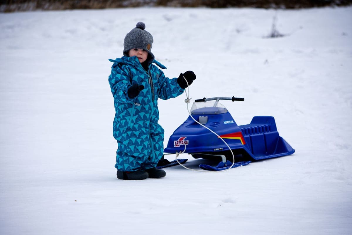 Young child in a snowsuit playing in deep snow on a winter day