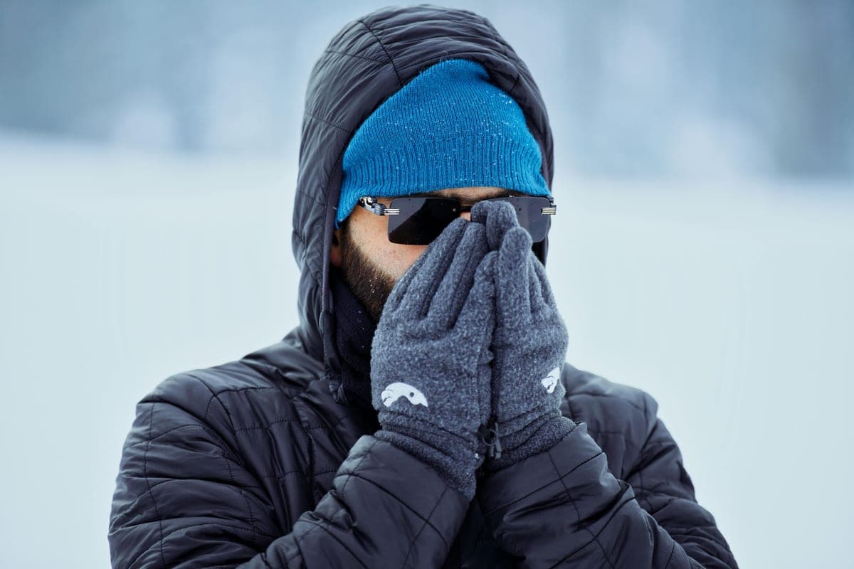 An adult in winter clothing with gloves outdoors in cold weather