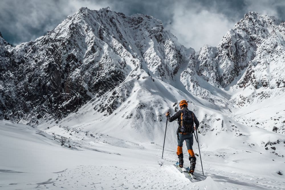 A skier in full gear standing in a snowy mountain landscape
