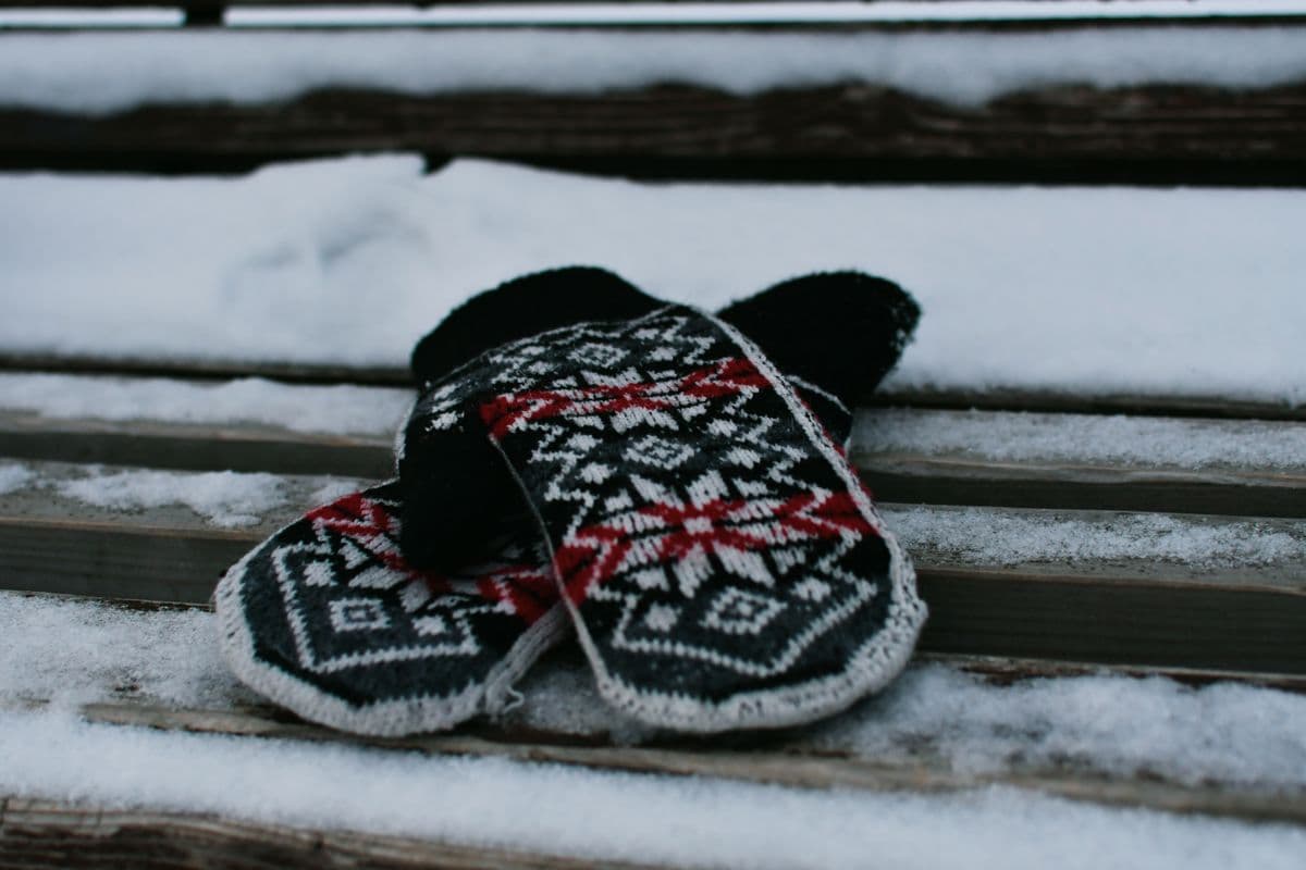 Knitted patterned mittens resting on a snowy bench