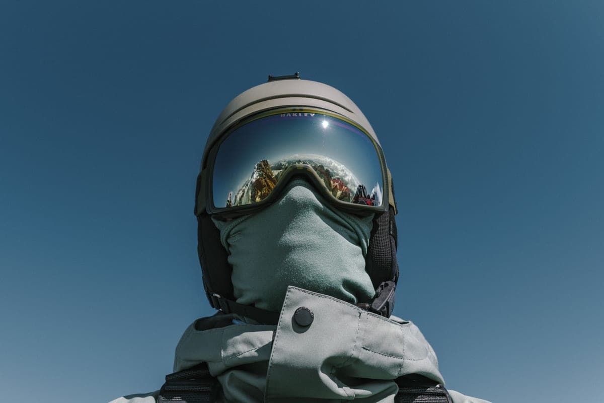 A skier in winter gear with the mountain reflected in their goggles