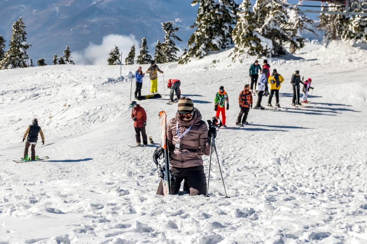 Group of skiers in winter jackets on a sunny snow-covered slope