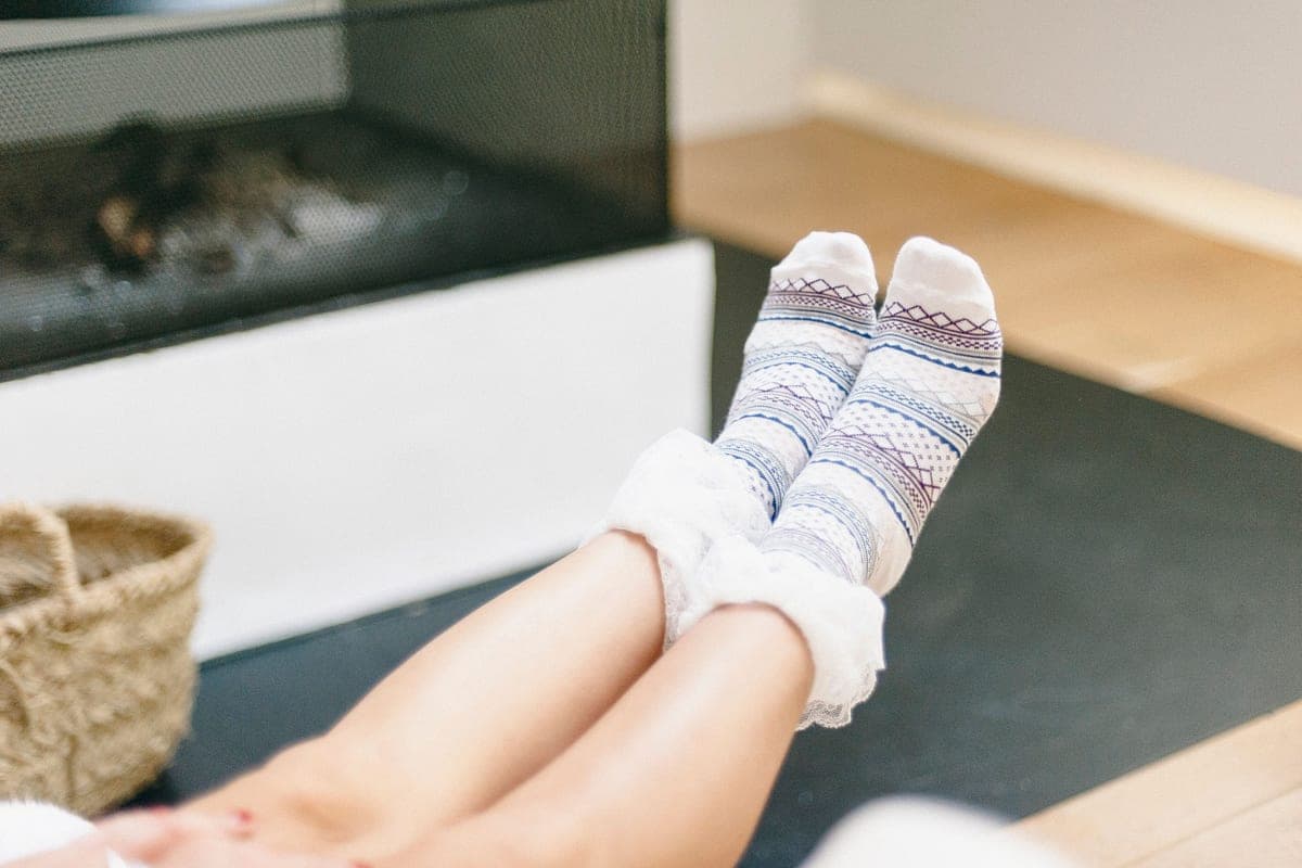 Warm patterned socks worn indoors in front of a fireplace