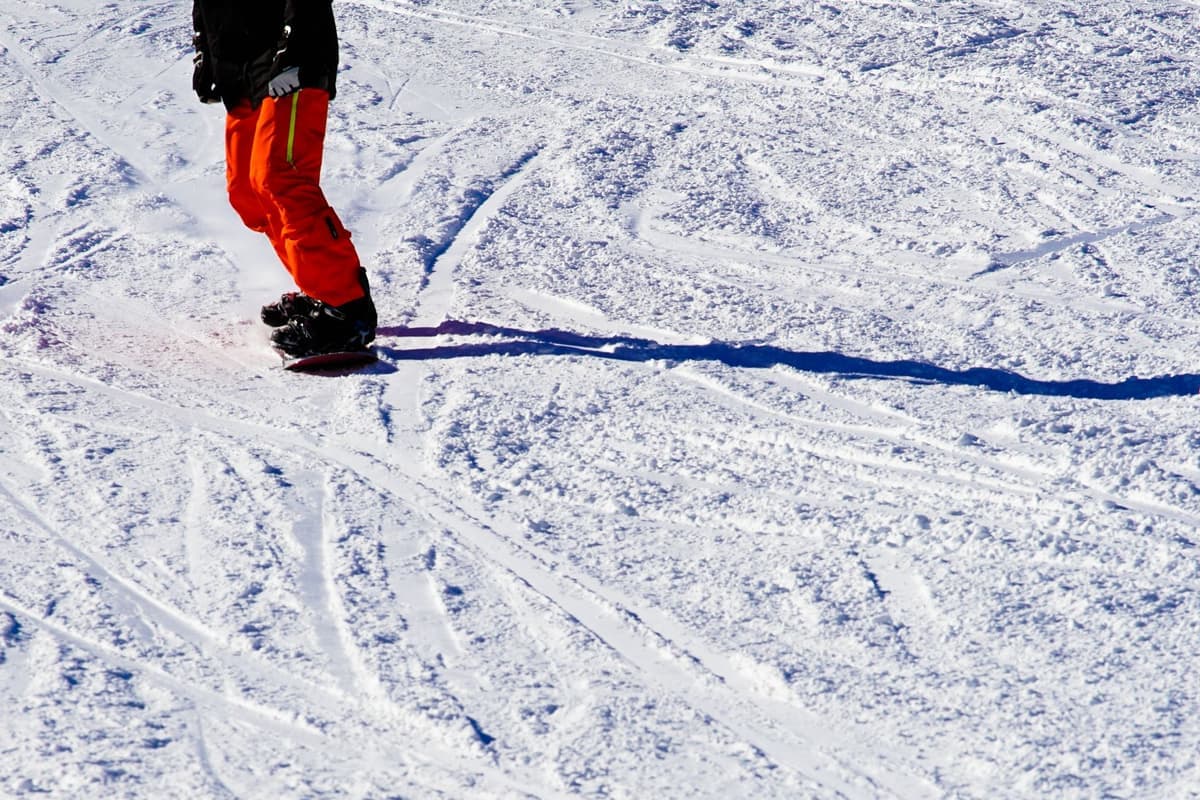 A snowboarder in snow pants riding a sunny slope in winter