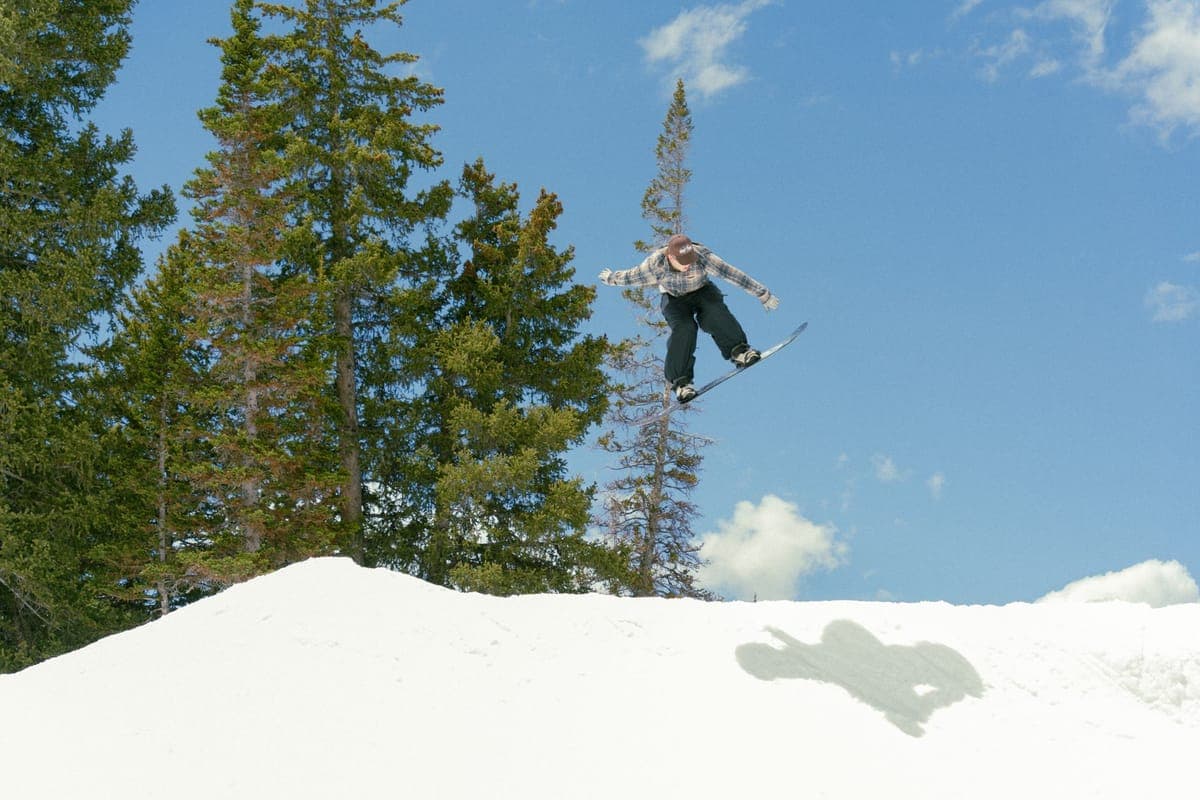 A snowboarder jumping against a bright blue sky on a sunny spring day