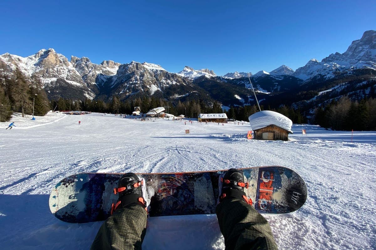 A snowboarder resting at a scenic alpine resort on a clear day