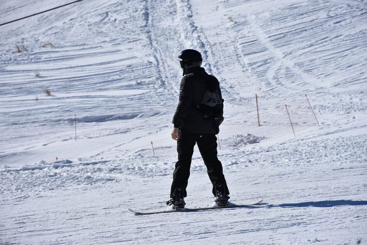 A snowboarder riding across a sunlit snow-covered slope