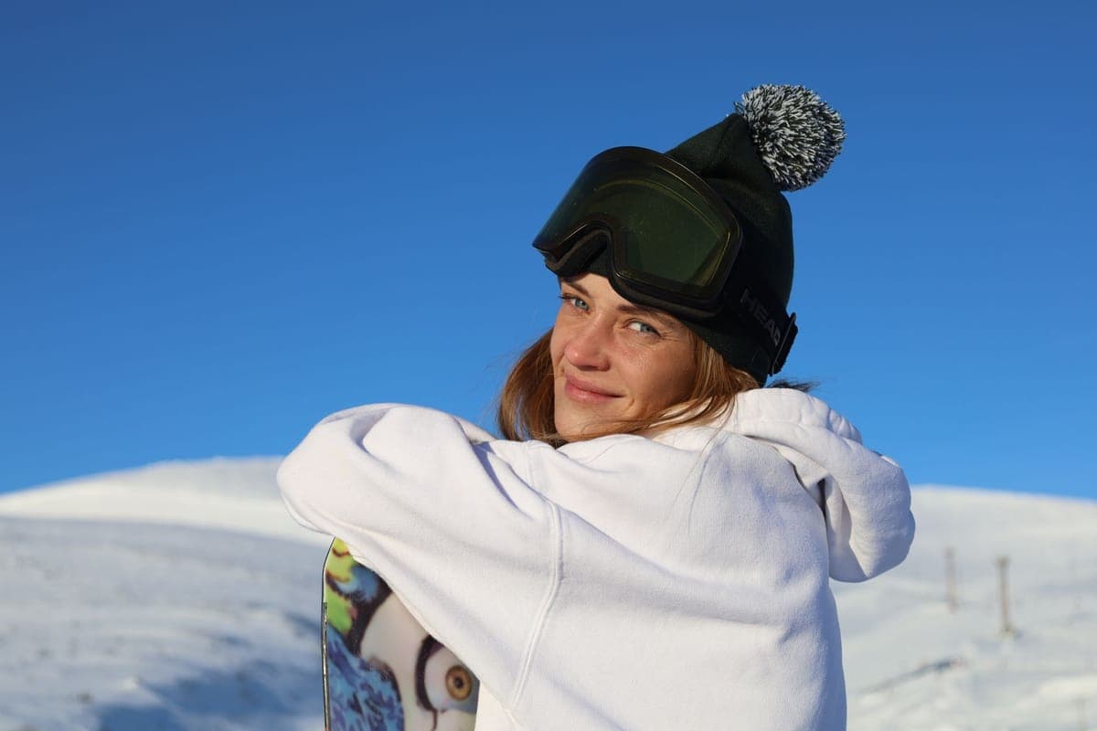 A snowboarder resting with a board on a sunny winter day